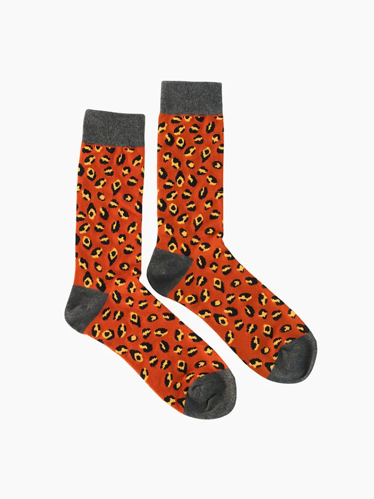 A pair of leopard - print socks with an orange base color, black and yellow spots, and gray cuffs and toes.
